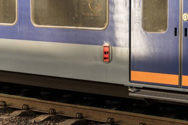 Tren vagonu, gün ışığı altında renkli dış tasarımı ve yapısal özelliklerini sergileyen demiryolu raylarının üzerinde duruyor..