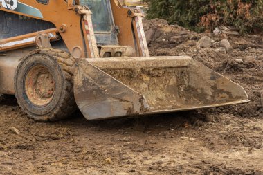 Bir inşaat aracı, gelecekte kalkınma için zemin hazırlamaya katkıda bulunarak, etkin bir şekilde bir alanda toprak hareket ediyor ve onları düzleştiriyor..