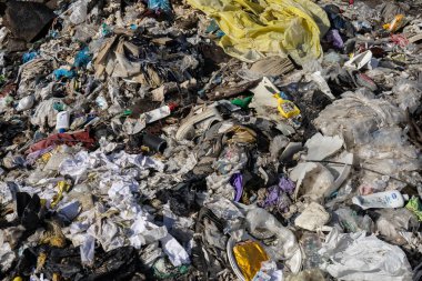 Şiddetli kentsel kirlilik sorunlarının altını çizen muazzam bir yığın karışık atık birikiyor, plastik ve kağıt kalıntıları sergileniyor.