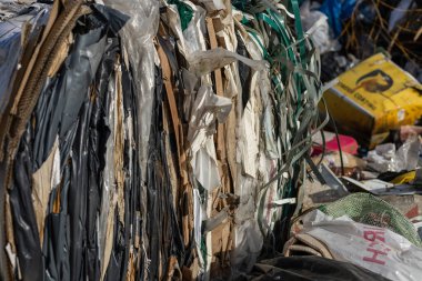 Sıkıca paketlenmiş geri dönüşümlü materyaller atık yönetim sahasında işleme konmak üzere hazırlanmakta olup, eylem sırasında sürdürülebilirlik çabaları gösterilmektedir.