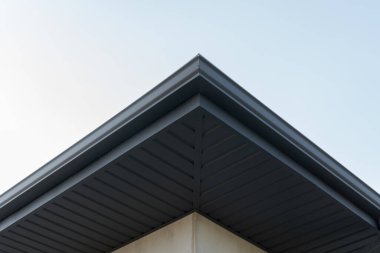 Çağdaş bir bina, yukarıdaki parlak mavi gökyüzü ile çelişen keskin çatı açısını ve temiz çizgilerini sergiler..