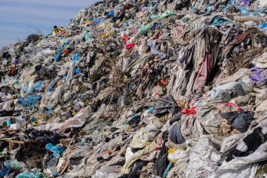 Giysiler, plastik ve çöplerle dolu büyük bir çöp yığını acil kirlilik sorunlarının ve geri dönüşüm ihtiyacının altını çiziyor.