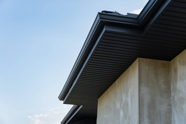 Modern bir binadaki metalik kiremit çatı döşemesi, parlak bir gökyüzü altında zanaat ve tasarım sergileniyor..