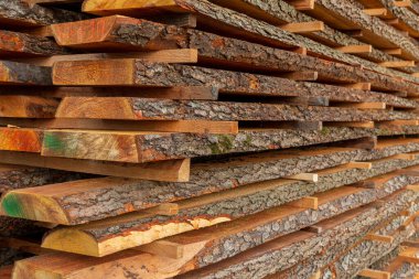 Düzgünce istiflenmiş ahşap kalaslar, kereste deposundaki ahşap işçiliği malzemelerini gösteren zengin dokuları ve renkleri ortaya çıkarır..