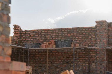 İnşaat işçileri, güneş ışığı çevreyi aydınlatırken sağlam bir duvar inşa etmek için inşaat alanlarına tuğla yığmakla meşguller..