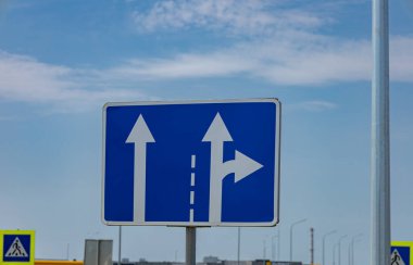 Trafik işareti, güneşli bir havada düz devam etme veya sağa dönme seçeneğini gösteren okları gösterir.