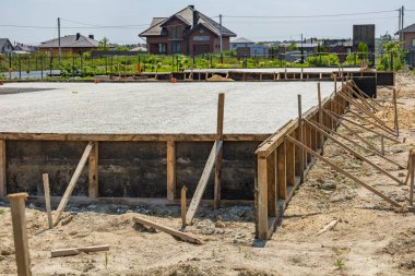 İşçiler, temiz gökyüzünün altında büyüyen bir banliyö mahallesinde konut projesi için somut bir temel hazırlıyorlar..