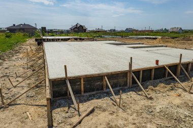 İşçiler, güneşli bir gökyüzü altında inşaat ilerledikçe sakin bir kırsal bölgedeki bir bina için sağlam bir temel oluşturdular..