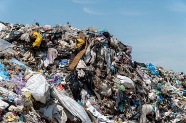 Güneşli bir günde bir çöp sahasında bulunan plastik ve organik maddelerden oluşan büyük bir yığın karışık atık..