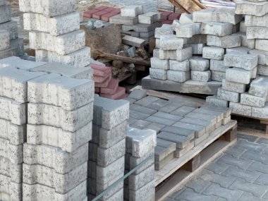 Parlak gün ışığında bir inşaat sahasında düzgünce dizilmiş beton ve tuğla bloklar, projeler için inşaat malzemeleri sergileniyor..