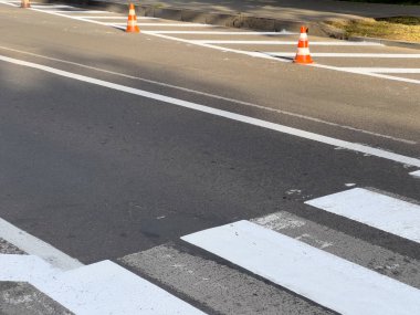 Gündüz saatlerinde kalabalık bir şehir caddesinde yol çalışması yapılırken, yaya geçidine trafik konileri yerleştiriliyor..