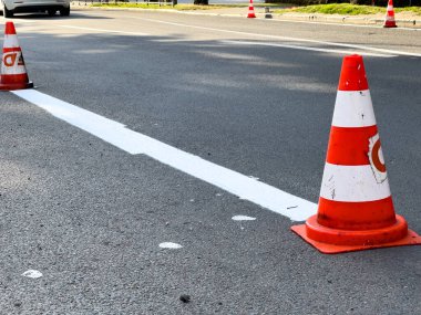 Trafik konileri, sürücülere güvenlik sağlamak amacıyla, yol bakımı sırasında kentsel alanda yeni boyanmış şerit boyunca konumlandırılmıştır..