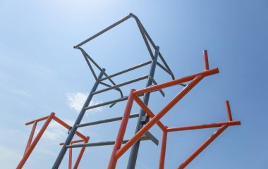 Renkli tırmanış yapısı, açık mavi gökyüzünün altında güzel güneşli bir parkta çocukların oynamalarını sağlar..