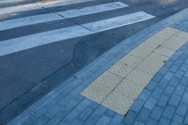 Yaya geçidi, şehir caddesinde işaretli beyaz çizgilerle görülebilir. Yanında da rehberlik için sarı dokunmatik asfalt var..