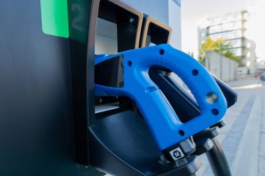 Mavi yakıt hortumu şehir ortamında bir yakıt istasyonuna yerleştirildi, gün ışığında araçların dolması için hazır..