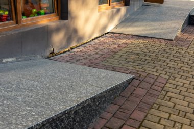 Granit bir kaldırım, öğleden sonra vakti penceresinde renkli oyuncaklar olan bir mağazanın önünde kırmızı ve gri kaldırım taşlarıyla buluşur..