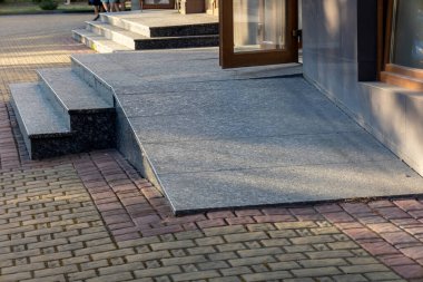 Somut bir erişim rampası kaldırımı bina girişine kusursuz bir şekilde bağlıyor ve kamu alanlarında kapsayıcılığı teşvik ediyor..