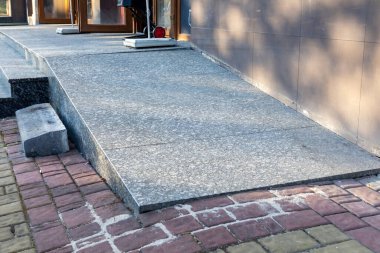 Erişilebilir rampa, gündüz saatlerinde birbirine zıt tuğla geçitli bir binaya sorunsuz giriş sağlar..