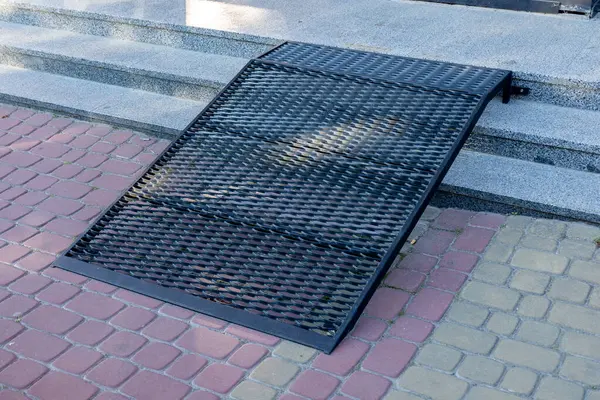 Kamu binasına giden basamakların üzerine yerleştirilen metal rampa, tekerlekli sandalye kullanan şahıslara erişim olanağı sağlıyor.