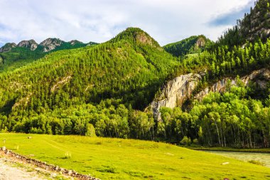 Dağları olan güzel bir manzara ve arkasında mavi bir gökyüzü.