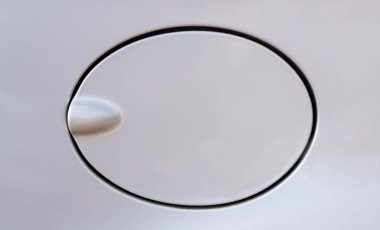 Açık gri bir arabanın yakıt deposuna erişmek için kapalı bir oval kapağın yakın plan görüntüsü..