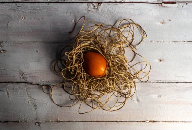 Açık renkli ahşap bir raftaki iplik yuvasında bir yumurta.