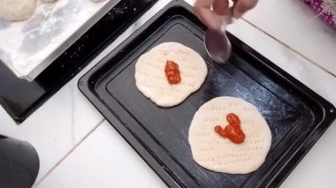Bu video kaydı hamurun üzerine sos dökme ve onu düzleştirme sürecini yakalar ve pizza ya da diğer yemekler için lezzetli bir temel oluşturur. Sürecin yukarıdan aşağı görünümü her adımı görmeyi kolaylaştırır ve doğru şekilde yaptığınızdan emin olur..