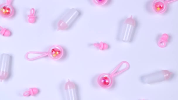 ピンクのガラガラ ペーパー ベビーボトルで回転する白い背景 新生児の女の子と女の子の誕生日の概念 高品質4K映像 — ストック動画