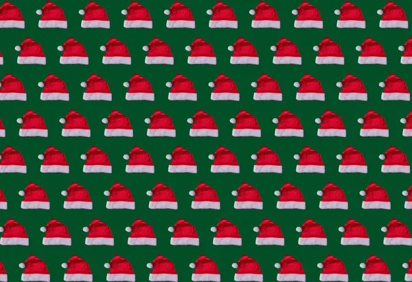 Yeşil arka planda Noel Baba şapkalarının Noel şablonunu tekrarlaması, şenlik şablonu, yeni yıl konsepti. Yüksek kalite fotoğraf