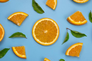 background with slides of orange and leaves on a blue background, trendy summer, fruity background.