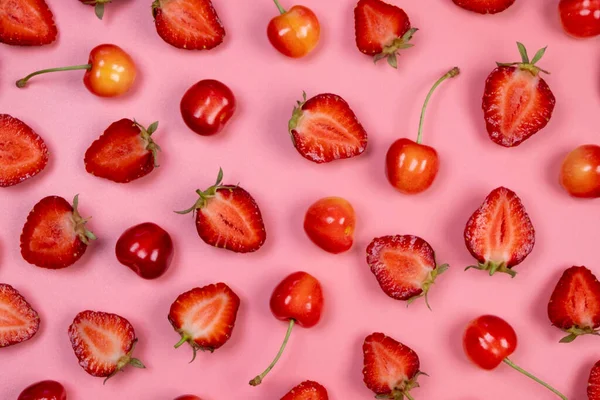 background of ripe strawberries and cherries on a pink background.Trendy,fruity,summer background. 