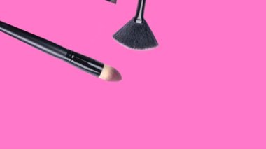 Değişik makyaj aksesuarları modaya uygun pembe arka plan üzerine düşüyor. Güzellik animasyonu. Kozmetik ürünler. Makyaj aletleri seti. Ruj, rimel, fırça, vernik düşüşü. Deri