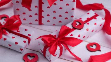 Kupa ve kırmızı kurdeleli kağıda sarılı hediye kutularıyla dönüşümlü kompozisyon. Sevgililer Günü 'nde, doğum gününde ya da diğer tatillerde hediye kutlaması için konsept. Yüksek kalite 4k görüntü