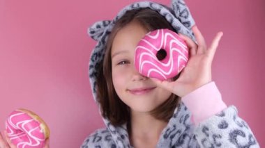 Kigurumi giymiş bir kız ya da pembe arka planda gözleri yerine donutlu bir pijama. Yüksek kalite fotoğraf