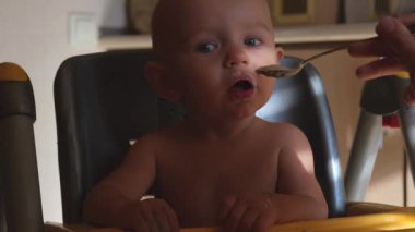 Çocuk pis yiyor, gülüyor ve gülümsüyor. Mutlu çocukluk hayali kavramı. Çocuk yulaf lapası suratında gülünç bir şekilde kirli, çocuk yemek yemeyi öğreniyor. Çocuk evde, sandalyede kirli yemek yiyor.