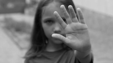 Girl showing stop sign gesture black and white photo. The child shows a palm, selectively focuses on five fingers. stop sign with hand saying no to domestic violence or abuse, discrimination strong