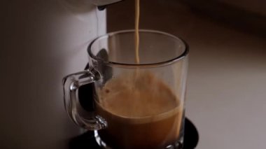 Kahve makinesinden ya da kahve makinesinden açık arkaplanlı şeffaf kupalara dökülüyor. Yüksek kalite 4k görüntü