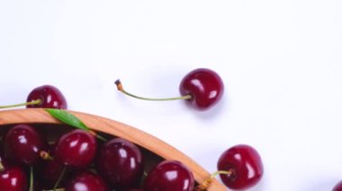 Beyaz arka planda olgun kırmızı kirazlarla dönen ahşap bir kase. Yüksek kalite 4k görüntü