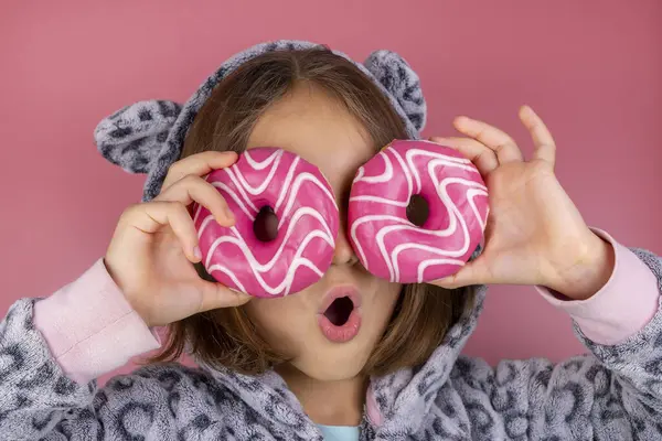 Kigurumi giymiş bir kız ya da pembe arka planda gözleri yerine donutlu bir pijama. Yüksek kalite fotoğraf