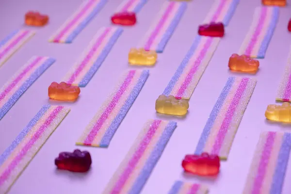  Çeşitli jöleli şekerlerin, ayıların, çöreklerin, şekerlemelerin arka planında pembe arka planda yakın plan konsept doğum günü partisi ya da kutlama . 