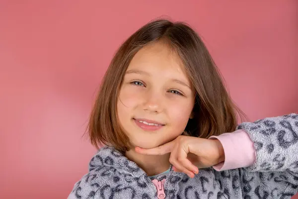 Güzel, gülümseyen esmer bir kızın portresi. Pembe arka planda, yakın plan pijamalarıyla 8 yaşında. Yüksek kalite fotoğraf