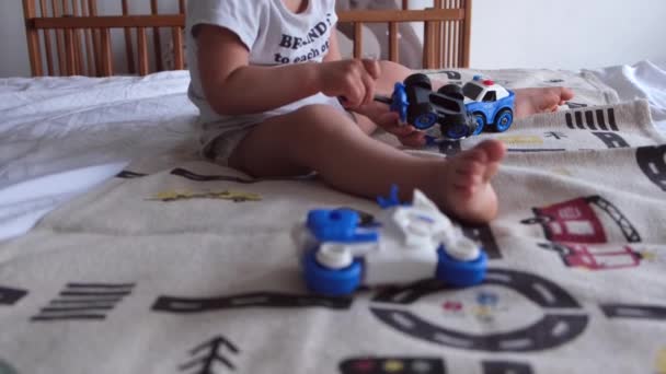 一个1或2岁的孩子在家里坐在床上修理汽车 玩螺丝刀和玩具警车 高质量的4K镜头 — 图库视频影像