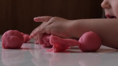 Bebek pembe plastik ve heykelciklerle oynuyor. Çocuklarla gelişim faaliyetleri, erken gelişim. Yüksek kalite 4k görüntü