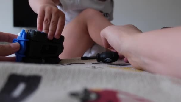 1歳または2歳の子供は ママと一緒に家でベッドに座っている車の修理でドライバーと玩具の警察車で遊びます ママは赤ん坊と遊んで手 高品質の4K映像 — ストック動画