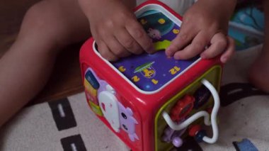 Bir bebek ya da 1-2 yaşındaki küçük bir çocuğun elleri oyuncak saat kepenkleri, eğitim oyuncakları ya da parmaklarının iyi motor becerilerini geliştirmek için bir küp, erken çocukluk gelişimi ile oynuyor. Yüksek