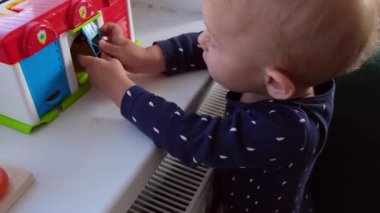 1-2 yaşındaki çocuk, evdeki pencerenin önünde garaj oyuncakları ve arabalarla oynuyor. Yüksek kalite 4k görüntü