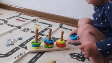 1-2 yaşındaki bir bebek ya da çocuk oyuncak piramitlerle, eğitici oyuncaklarla oynar ya da parmaklarının iyi motor becerilerini, çocuğun erken gelişimini geliştirmek için. Yüksek kalite 4k görüntü