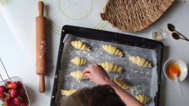 Kruvasan ya da simit pişirmek ya da evde kek pişirmek, çocuk mutfakta yemek pişirmek, yakın çekim yapmak, ev rahatlığı. Yüksek kalite 4k görüntü
