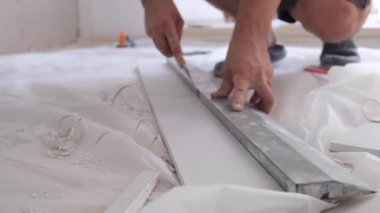 Profesyonel bir tamircinin elleri alçıdan yapılmış bir yaprağı bıçakla kesmiş. - konsept - onarım, inşaat malzemeleri, teknoloji. Yüksek kalite 4k görüntü