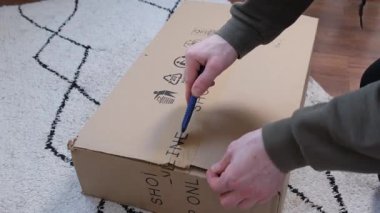 Kırtasiye bıçağıyla eli olan bir adam posta kutusunu açıp yakın plan kesiyor. Adam paketleri boşaltıyor. Genç adam e-ticaret ya da çevrimiçi market kutusunu açıyor. Yüksek kalite 4k görüntü